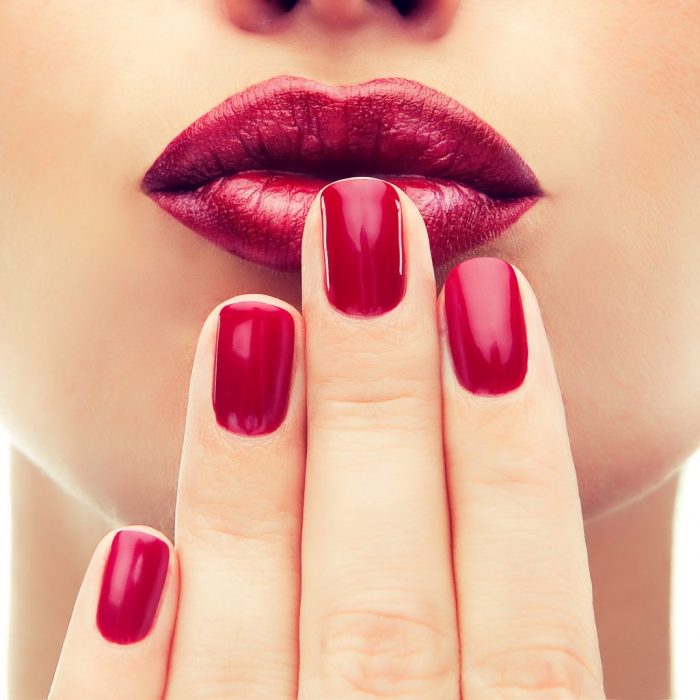 Beautiful model  shows red  manicure on nails. Red lips .Luxury fashion style, manicure nail , cosmetics and makeup .